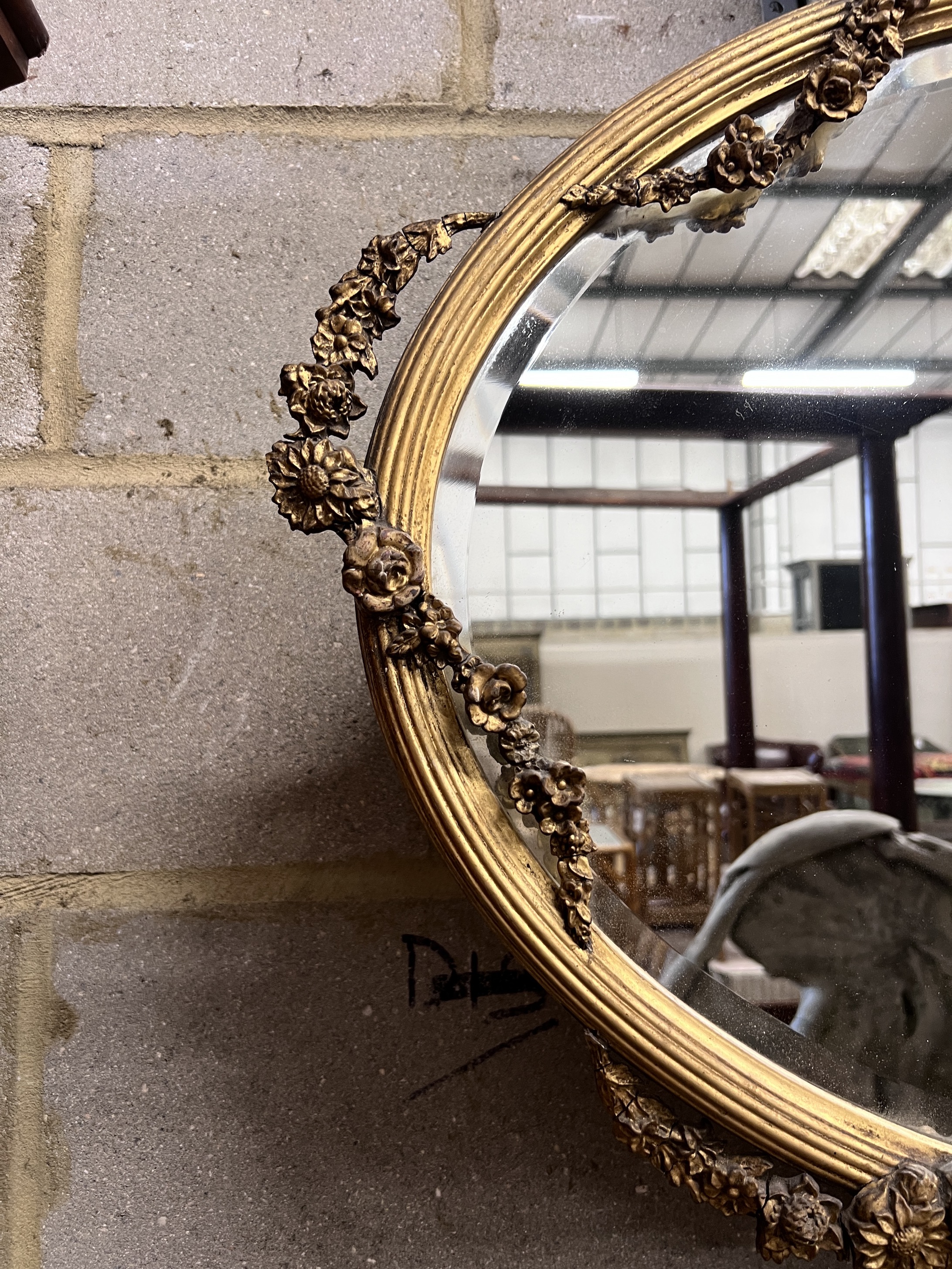 An Edwardian oval giltwood and gesso wall mirror with ribbon and flower swagged border, width 87cm, height 68cm